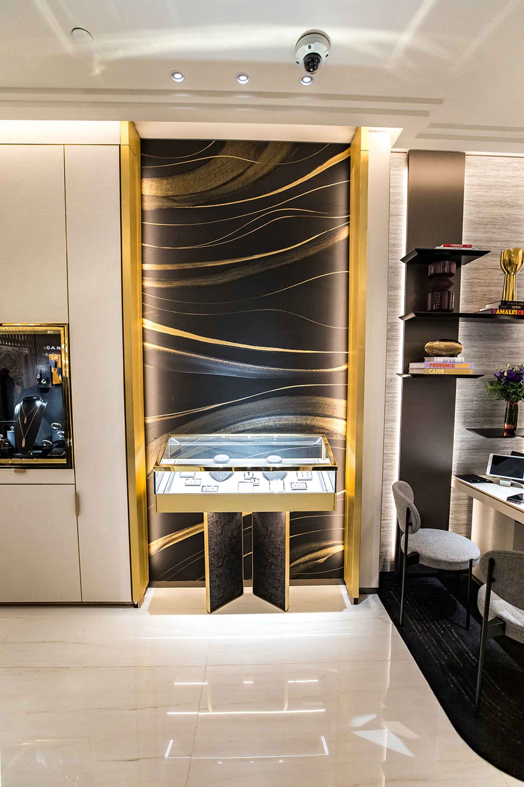 Un gros plan sur un présentoir en verre doré adossé à un panneau mural décoratif aux motifs de vagues noires et or.