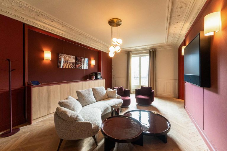 Un salon de réception sophistiqué combine des murs pourpres, un canapé courbe en bouclette blanche et un parquet en point de Hongrie.
